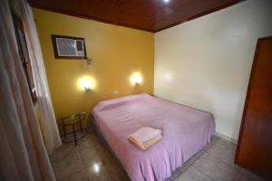 a small bedroom with a bed with a pink blanket at Hotel Lilian in Puerto Iguazú