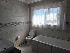 a bathroom with a tub and a toilet and a window at CE Guesthouse in Vanderbijlpark +25 photos