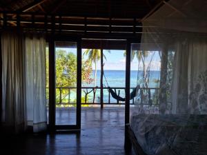 a bedroom with a hammock and a view of the ocean at Banua Guesthouse in Pulau Malenge