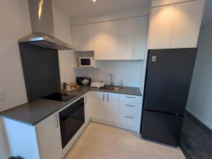 a small kitchen with white cabinets and black appliances at Gumlands Retreat in Auckland
