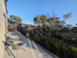 two chairs and a table on a balcony at Gumlands Retreat in Auckland +2 photos