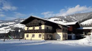 una casa en la nieve con montañas en el fondo en Rieserhof/Fam. Meißnitzer, en Taxenbach