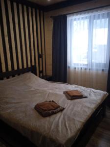 a bed with two towels on it with a window at Котедж Арпад in Synevyr