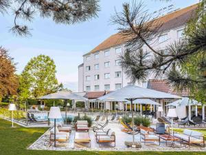 a group of chairs and umbrellas in front of a hotel at Novotel Beaune in Beaune