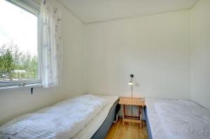 two beds in a room with a table and a window at Beautiful bright summer cottage in Skovbyballe