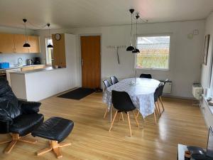 a living room with a table and chairs and a kitchen at Beautiful bright summer cottage in Skovbyballe +7 photos
