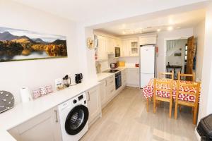 a kitchen with a washing machine and a table and chairs at Hill Cottage, Braithwaite with garden and fell views, dog friendly walks from the door, close to Bassenthwaite in Braithwaite