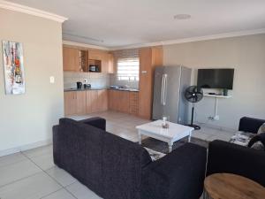a living room with a couch and a kitchen at CE Guesthouse in Vanderbijlpark