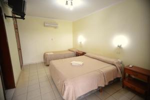 a hotel room with two beds and a television at Hotel Lilian in Puerto Iguazú