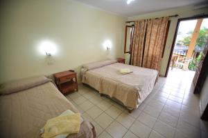 a hotel room with two beds and a balcony at Hotel Lilian in Puerto Iguazú
