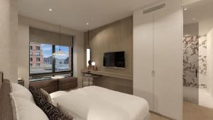 a bedroom with a large white bed and a tv at Van der Valk Hotel Maastricht-Maas in Maastricht