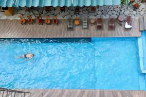 a man swimming in a swimming pool withroups of chairs at Tam Coc Lion Kings Hotel & Resort Ninh Binh in Ninh Binh