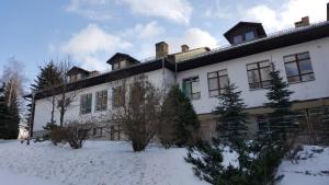 Un grand bâtiment blanc avec de la neige au sol dans l'établissement Dom wczasowy Lubuszanin, à Podgórzyn