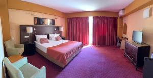 a hotel room with a bed and a television at Boeme88 in Eforie Sud