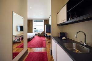 a kitchen with a sink and a room with a bed at Rendezvous Heritage Hotel Auckland in Auckland