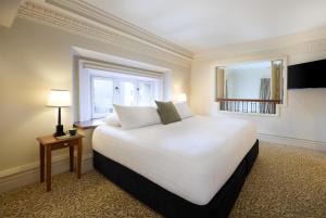 a large white bed in a room with a window at Adina Heritage Christchurch in Christchurch +38 photos