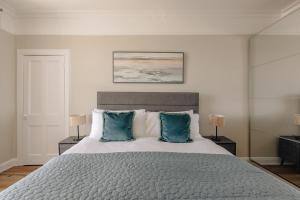 a bedroom with a large bed with two blue pillows at At Anchor (with a Harbour View) in Fife