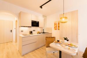 a kitchen with white cabinets and a table with food on it at Apartments GoldRain in Coldrano