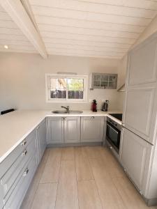a kitchen with white cabinets and a sink and a window at Chalet Familial 6 personnes in Gujan-Mestras