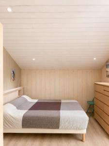 a bedroom with a bed and a wooden wall at Chalet Familial 6 personnes in Gujan-Mestras +13 photos