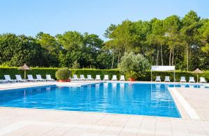 a large swimming pool with lounge chairs and trees at Chalet Familial 6 personnes in Gujan-Mestras