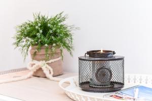 a candle on a table with a plate and a plant at Ferienwohnung to Huus in Bensersiel