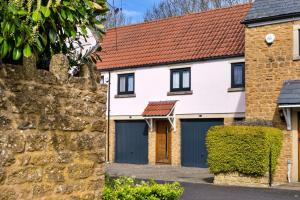 a house with two garage doors and a brick wall at Finest Retreats - Hollies Coach House in Martock