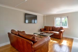a living room with two leather couches and a table at Finest Retreats - Hollies Coach House in Martock