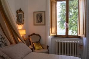 a bedroom with a bed and a chair and a window at Casa Sole di Toscana USO ESCLUSIVO con 5 camere, 3 bagni, terrazza panoramica, giardino e vasca idromassaggio in Monterotondo