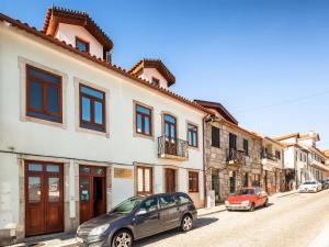 eine Straße mit zwei Autos, die vor einem Gebäude geparkt sind in der Unterkunft Casa Dos Ruis - Turismo Rural in Tabuaço