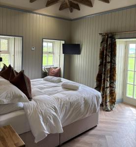 a bedroom with a large bed with white sheets at The Lodges @ Barra Castle in Inverurie