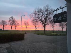 a sunset in a park with trees and a street sign at B&B Bokkeleane in Kolderwolde