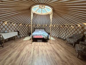 a room with a bed in a yurt with a window at Jimmy's Yurt in Shenley
