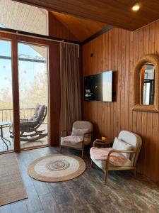 a living room with chairs and a tv and a balcony at Bruno House in Almaty