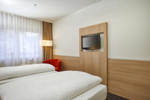 a hotel room with two beds and a flat screen tv at H+ Hotel Darmstadt in Darmstadt