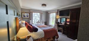 a bedroom with a bed and a desk and a television at Knipoch House Hotel in Oban