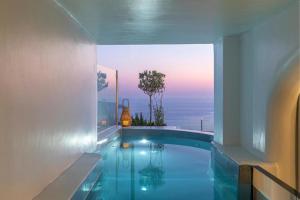 a swimming pool with a view of the ocean at Diamond on the cliff Hotel&Suites Imerovigli in Imerovigli
