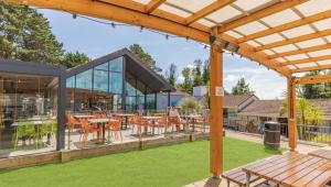 an outdoor patio with tables and chairs in a building at Newquay - Deluxe 3 bed Lodge Willows Way 47, Newquay Parkdean, Holiday Park in Newquay