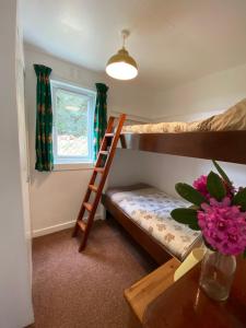 a bedroom with two bunk beds and a table with a vase of flowers at Lochead Chalet 1 in Lochgilphead
