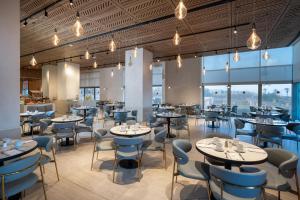 a restaurant with tables and chairs and windows at Leonardo Plaza Haifa in Haifa
