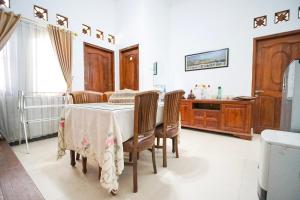 a dining room with a table and chairs and a kitchen at Ndalem Artho in Beran-kidul