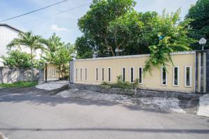 a yellow building with windows and a fence at Ndalem Artho in Beran-kidul