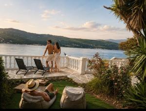 a man and a woman standing on a balcony overlooking the water at Villa ZeN- with Private garden and beach in Samos