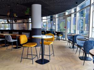 a restaurant with tables and chairs and windows at Hôtel Mercure Lyon Centre Charpennes Parc de la Tête d'Or in Villeurbanne