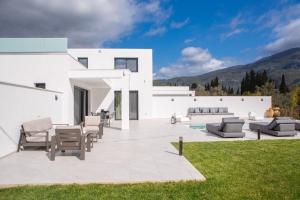 a white house with a patio and lawn at Amalfi Twins Villa in Nydri
