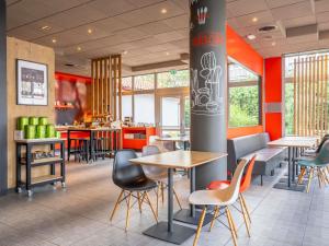 a restaurant with tables and chairs and red walls at ibis Bayonne Centre in Bayonne
