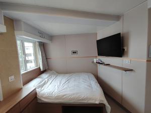 a small bedroom with a bed and a flat screen tv at Ocean Inn in Hong Kong