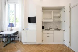 a kitchen with white cabinets and a table at SINONDA Luxury Apartment in Maiori