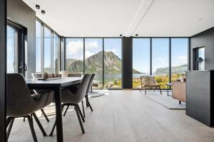 a dining room with a table and chairs and mountains at Lyngvær Arctic Pearl Lodge - Jacuzzi & Sauna - No 17 in Kleppstad +32 photos
