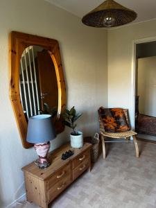 a lamp on a dresser with a mirror and a chair at Spacious house in cozy Kristdala in Kristdala